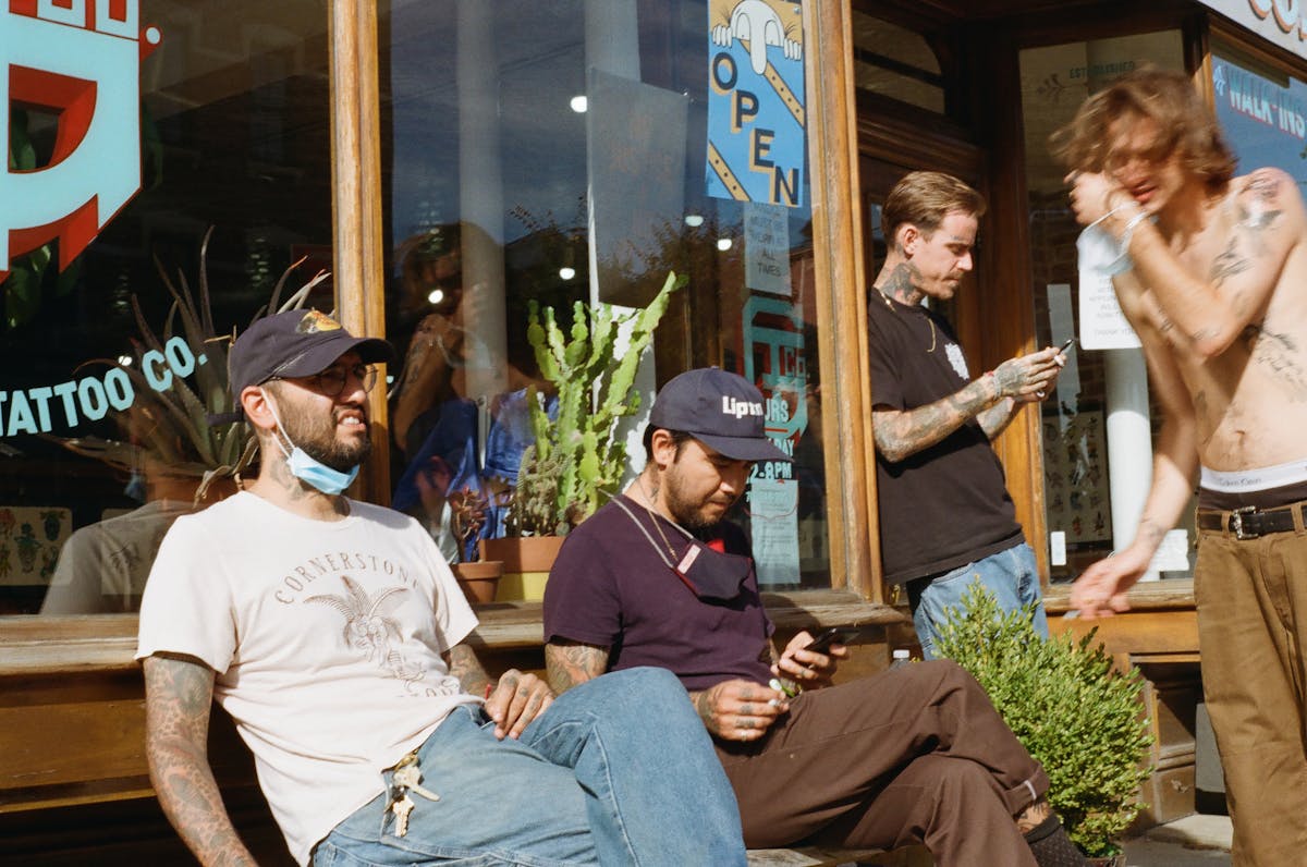 a group of people sitting on a bench outside greenpoint tattoo