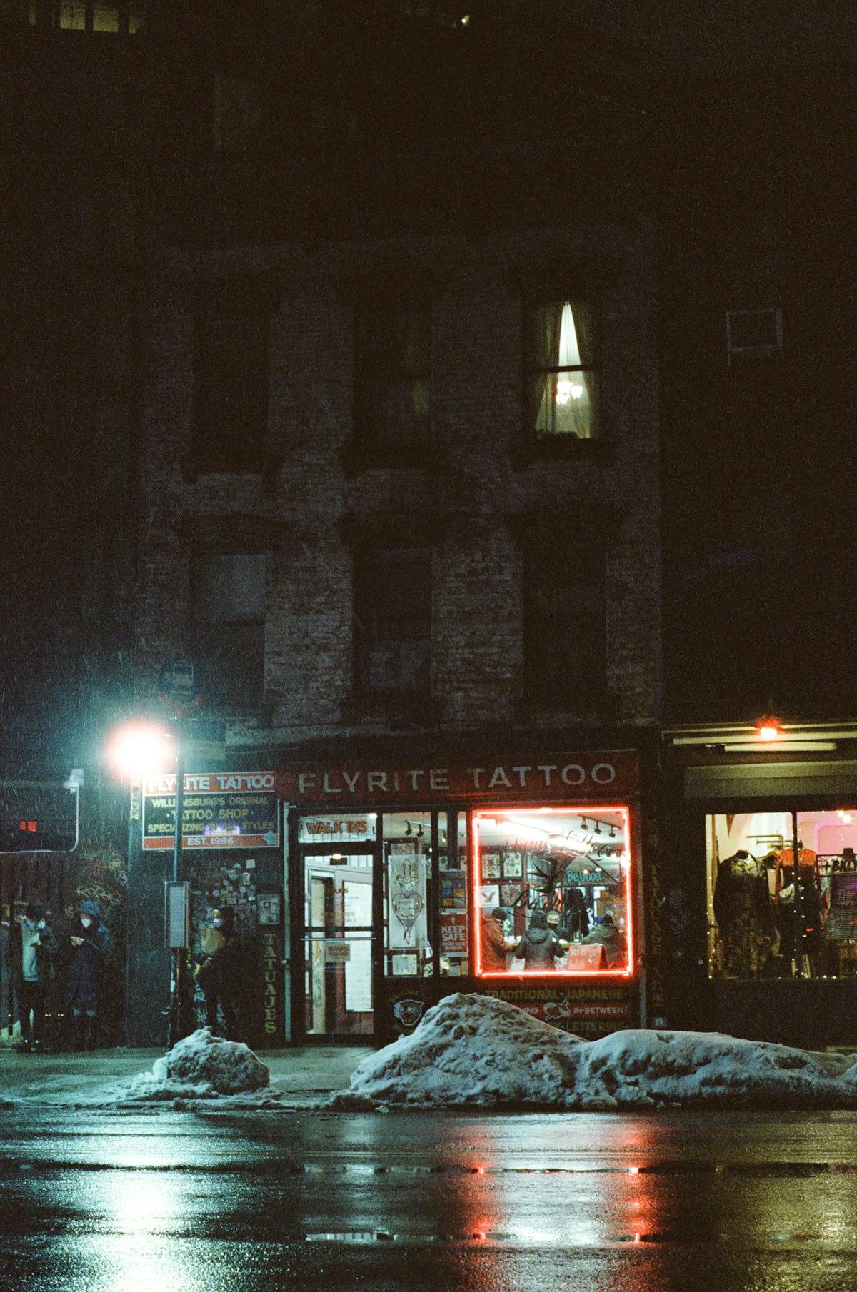 a building lit up flyrite tattoo brooklyn at night