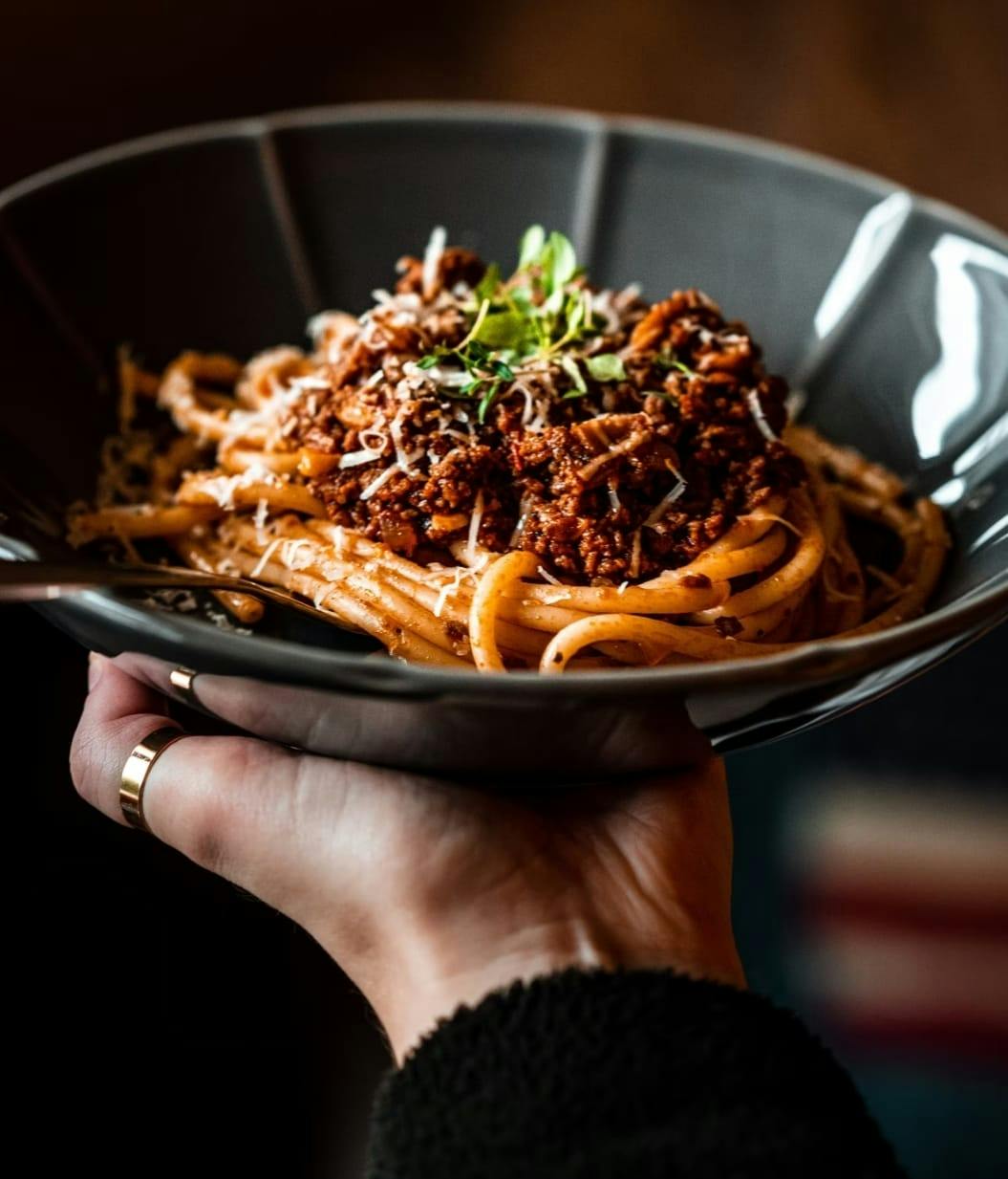 Person holding a pasta meal from The Tavern at Trails End