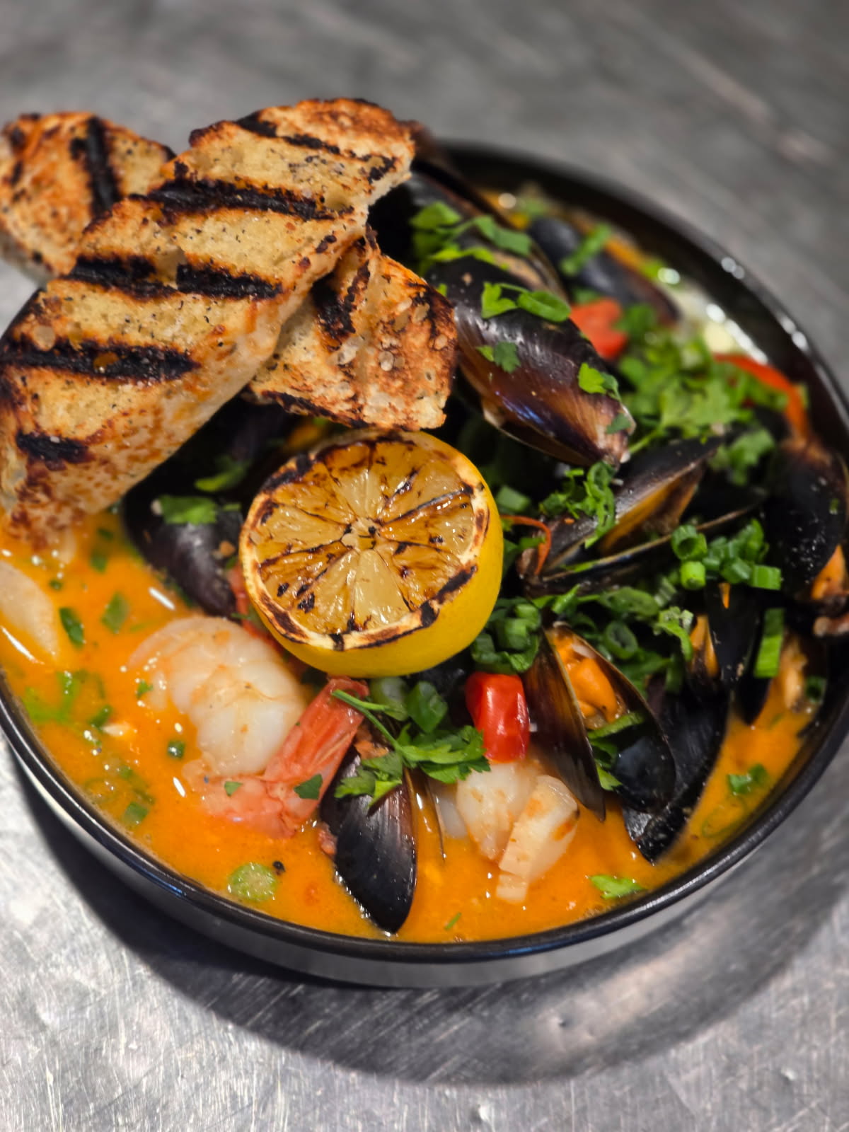 a bowl of soup with seafood and toast