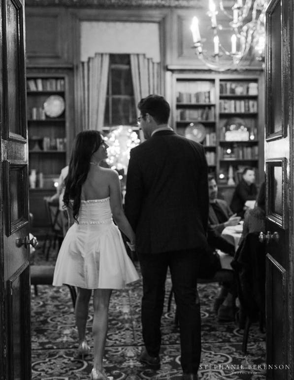 A newly engaged couple enter the room hand in hand to welcome their guests.