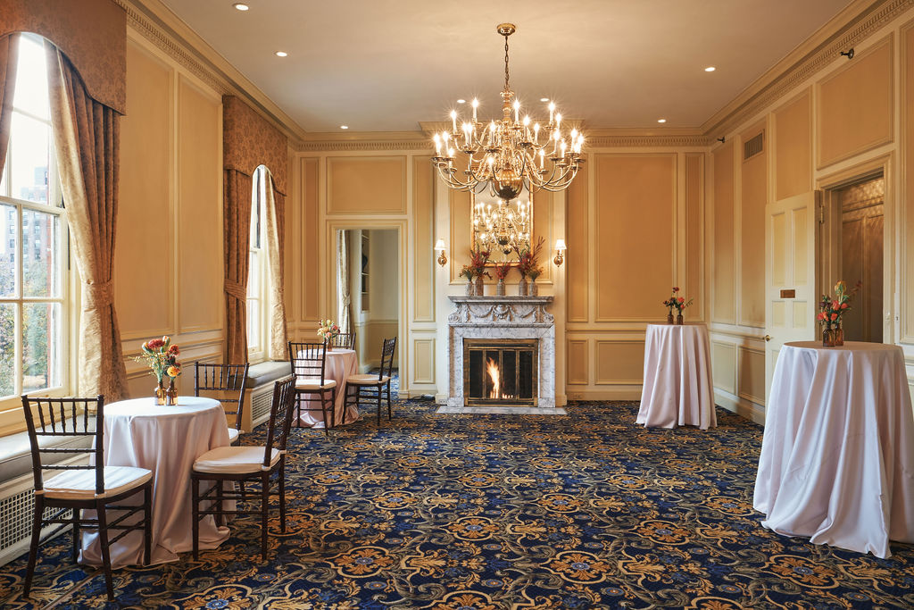 a room filled with tables and chairs and a fireplace