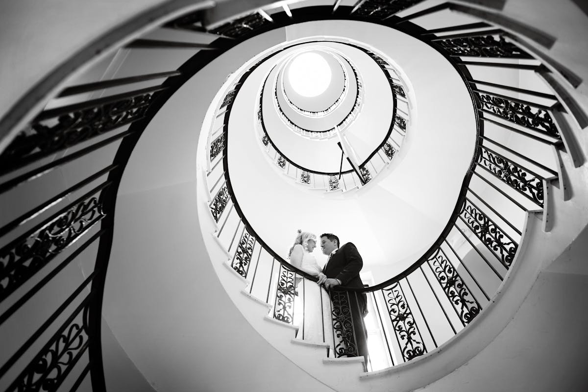 a bride and groom on a spiral staircase
