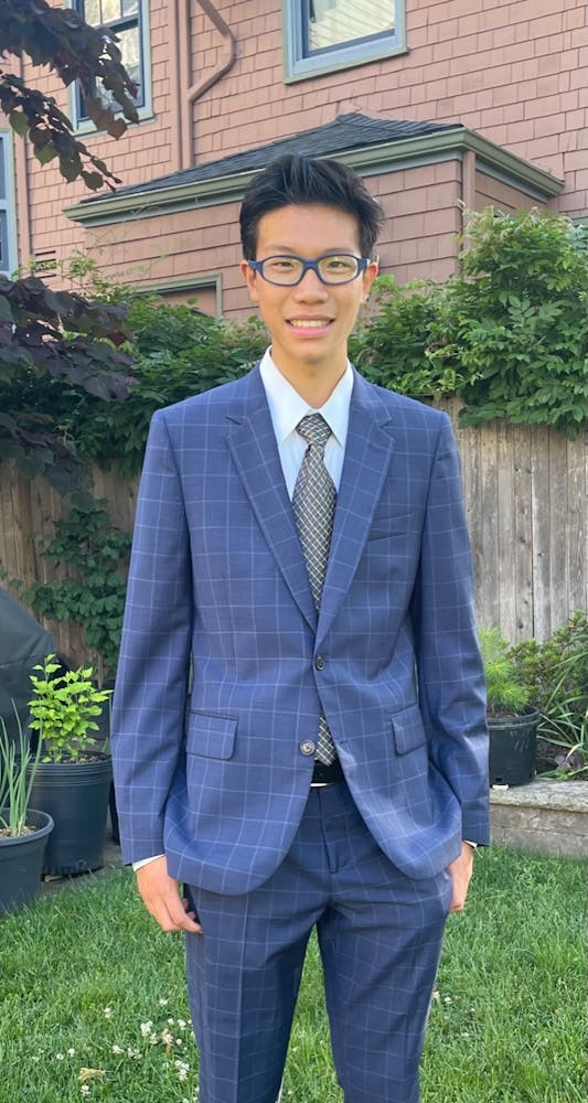 a man wearing a suit and tie standing in front of a building