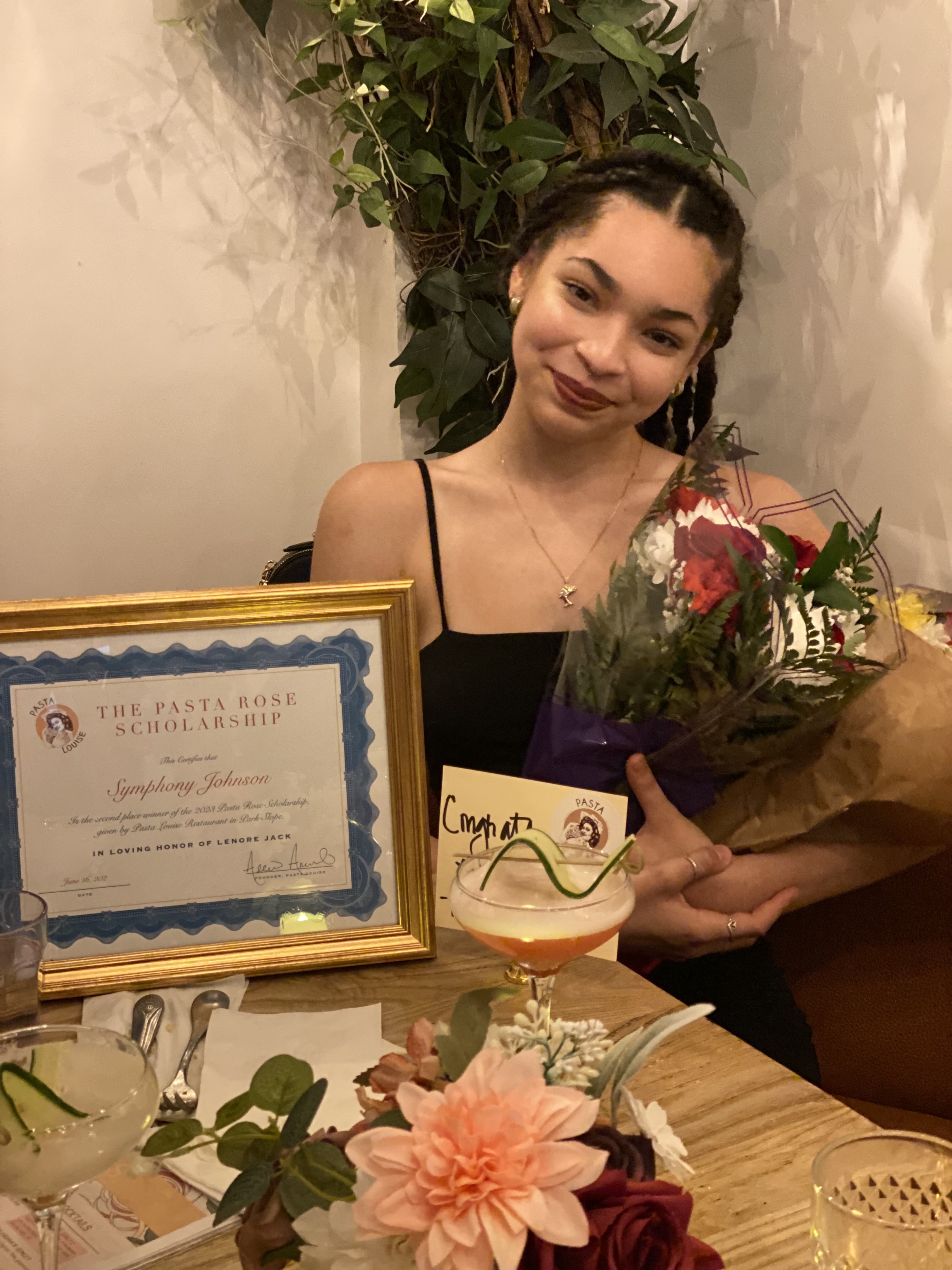 a woman sitting at a table with a vase of flowers