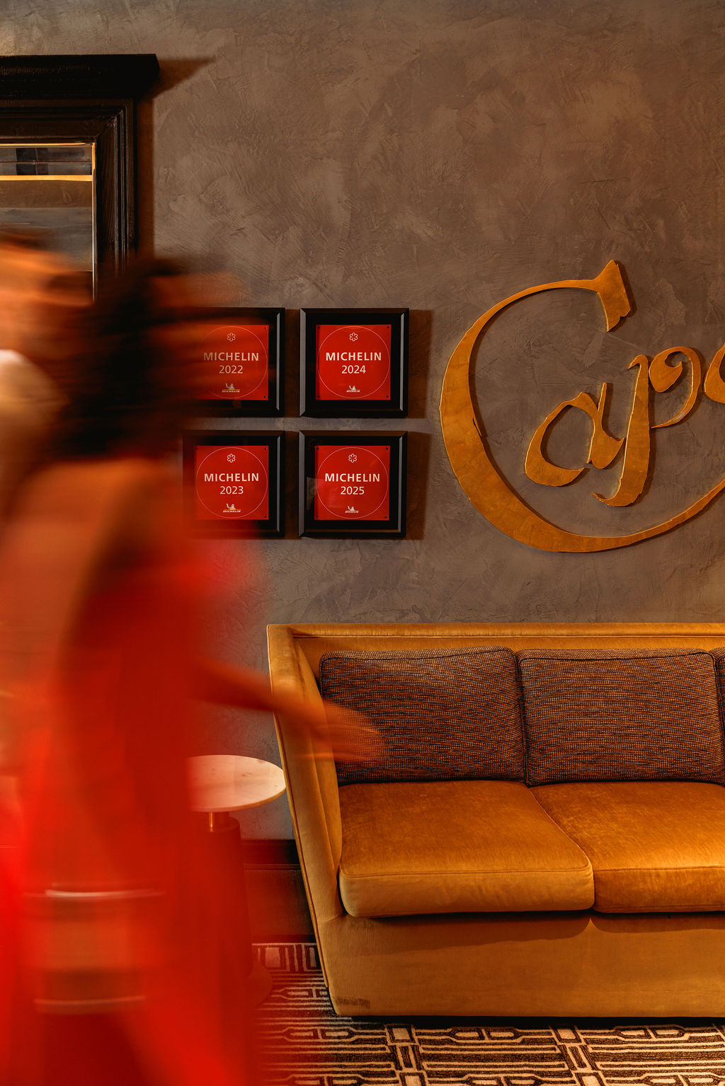 a woman in a red dress in front of a wall with a couch and a sign