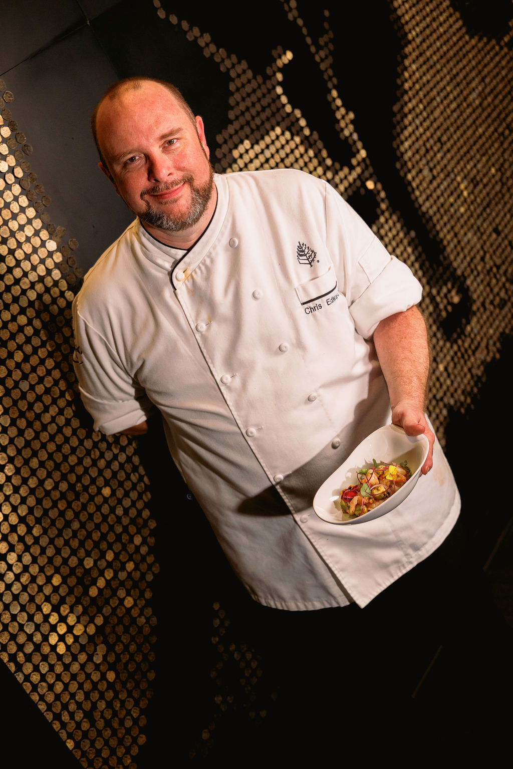 a man in a chef's uniform holding a plate of food