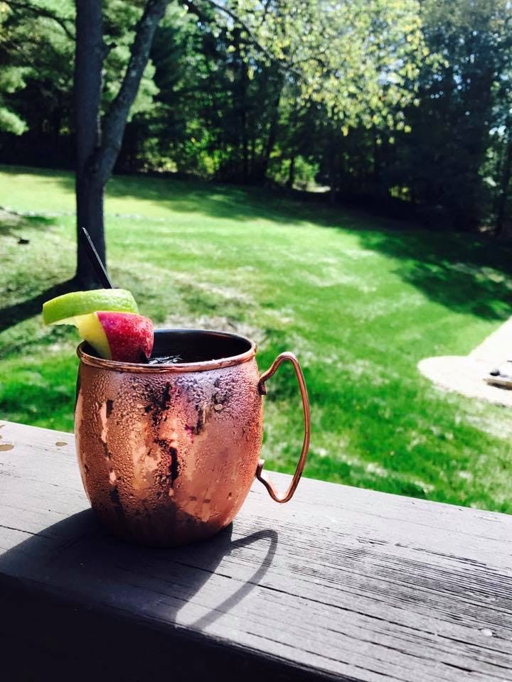 closeup of a moscow mule drink with a green field behind it