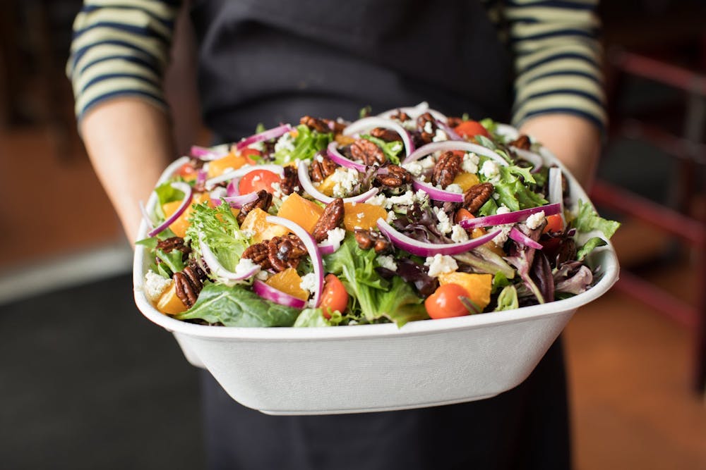 a person holding a bowl of salad