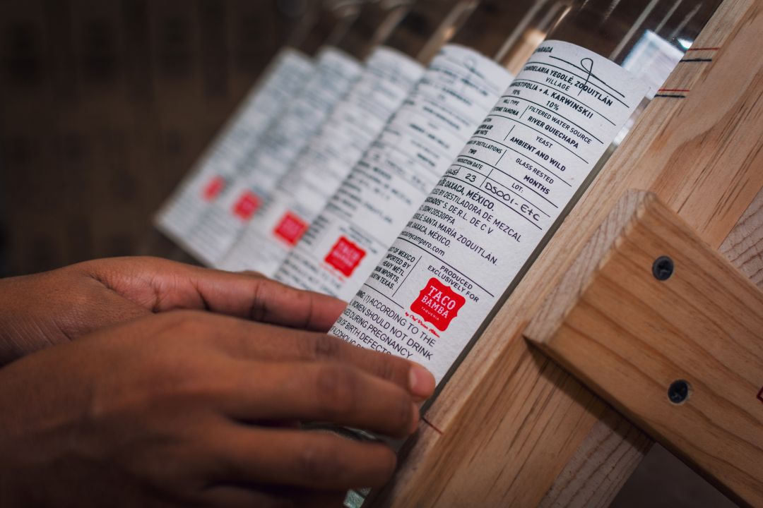 Process of labeling Rey Campero exclusive Taco Bamba private label mezcal with a Taco Bamba logo on the back.