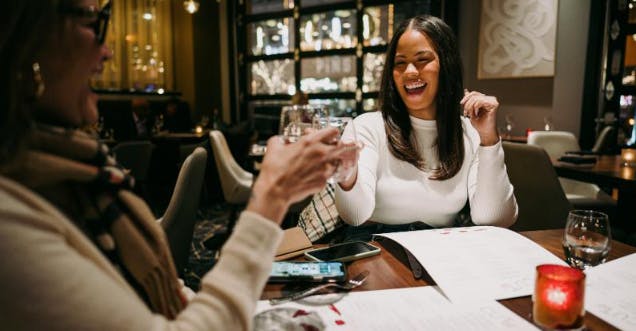 a woman sitting at a table with wine glasses