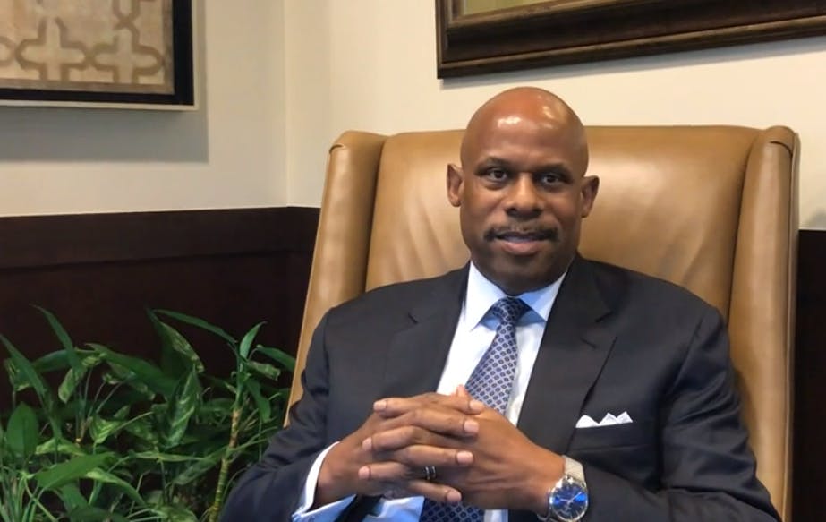 a man wearing a suit and tie sitting in a chair