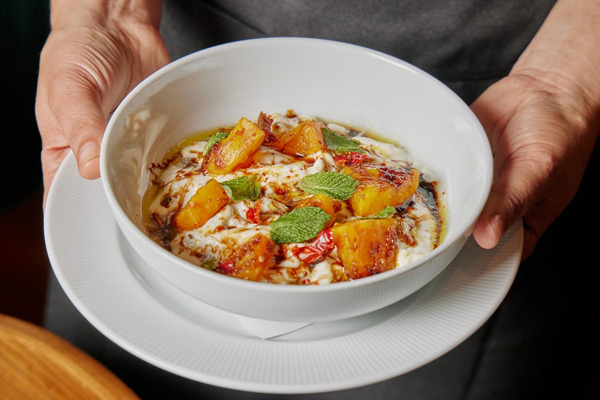 a hand holding a bowl of food on a plate
