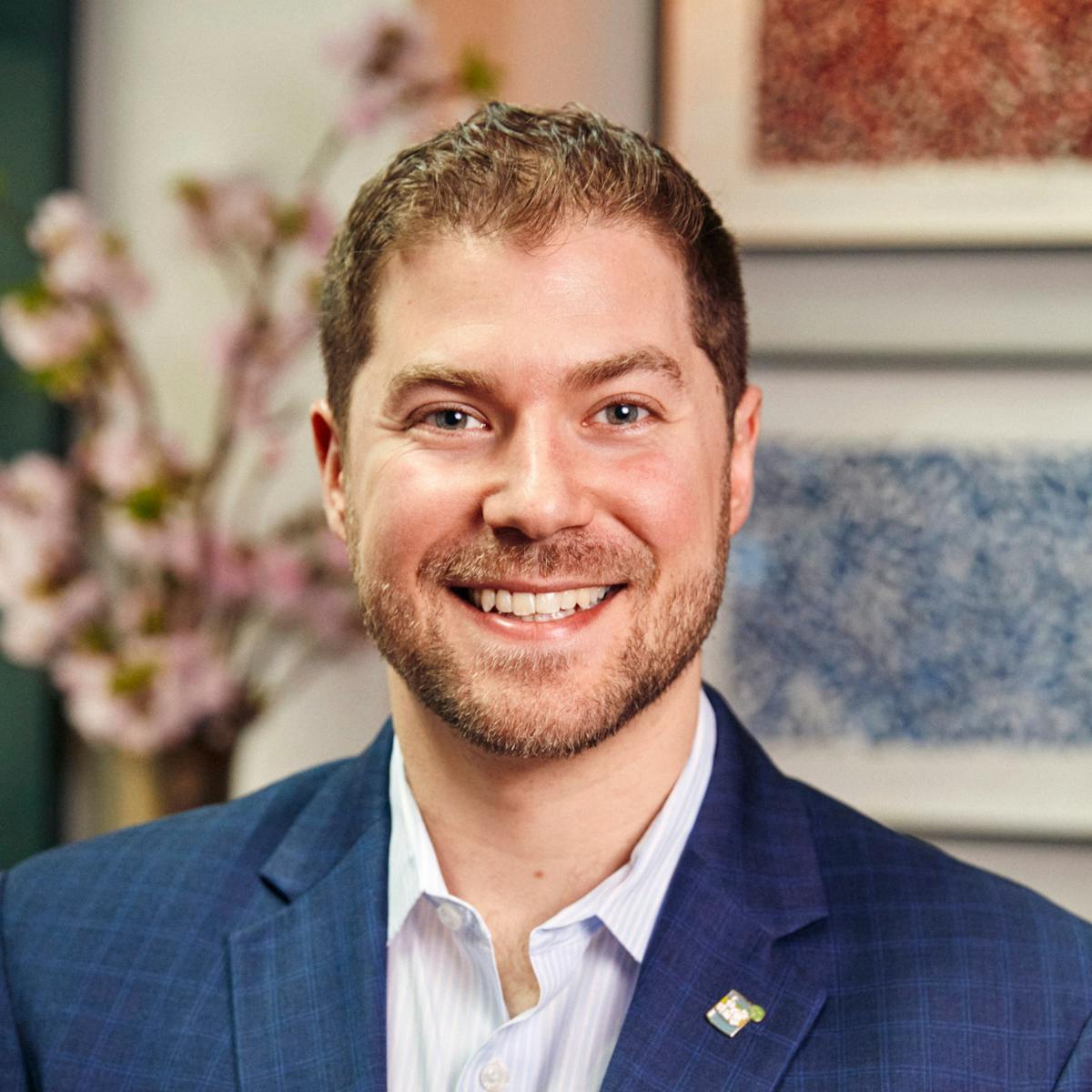 a man wearing a suit and tie smiling at the camera