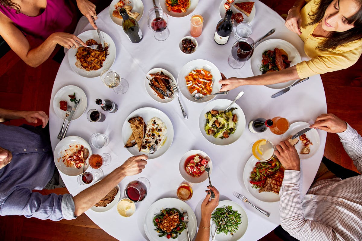 a group of people sitting at a table with a plate of food