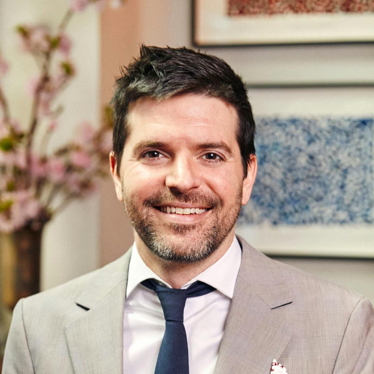 a man wearing a suit and tie smiling at the camera