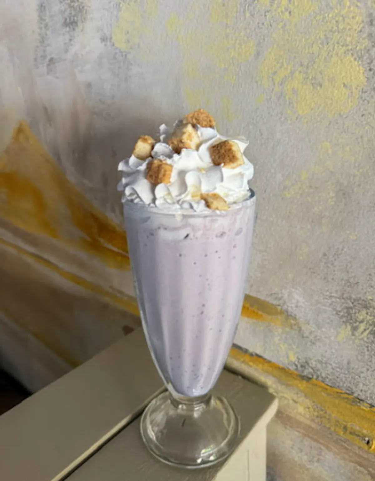 a glass of milkshake with whipped cream and creme on top