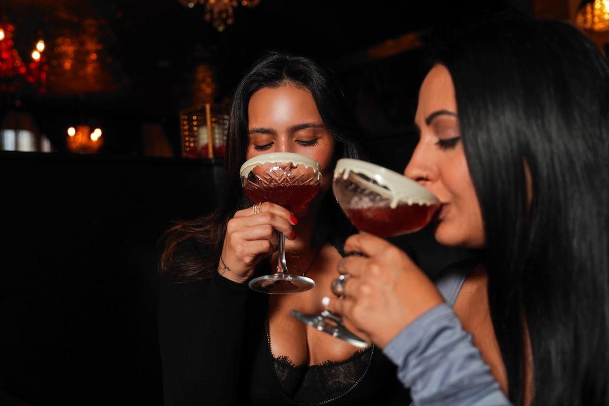 Close up of two women sipping on chocolate rimmed cocktails at Better Than Sex - A Dessert Restaurant