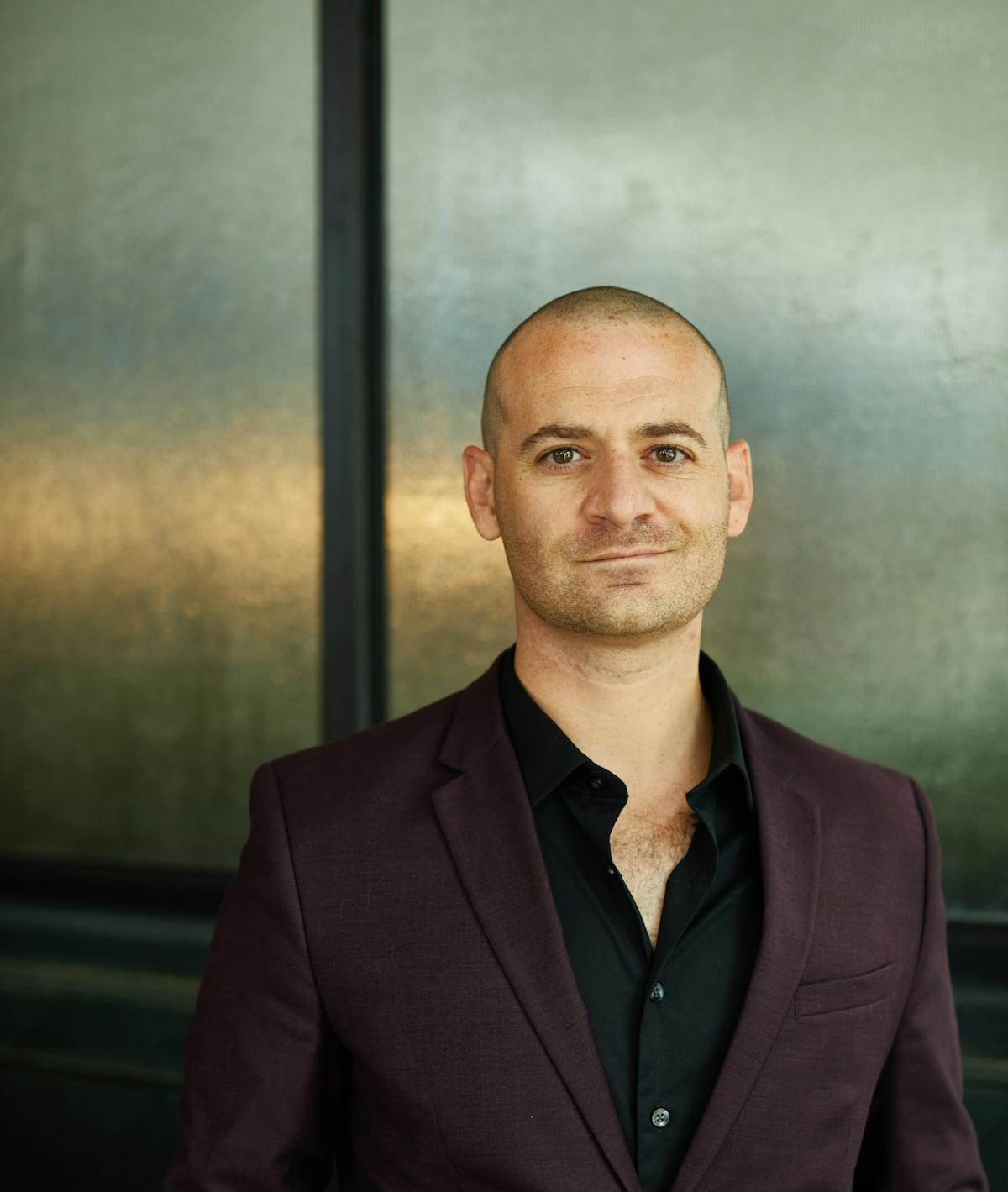 a man wearing a suit and tie smiling at the camera