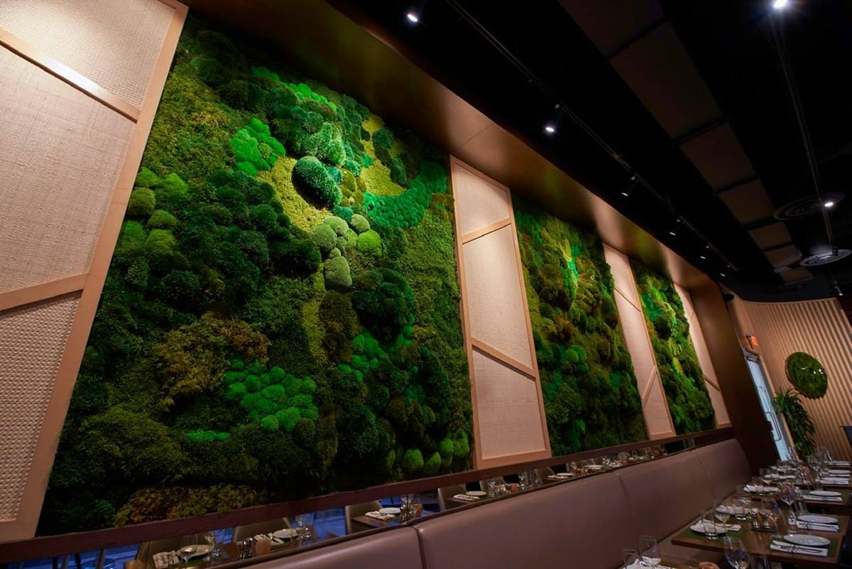 The interior of 1776 Restaurant showcases a striking wall of moss, creating a unique and inviting dining atmosphere.