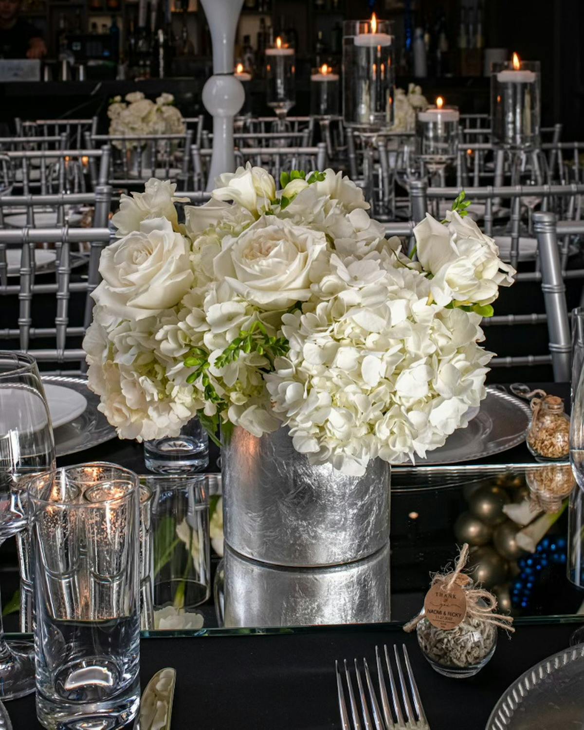 A charming table display with gleaming silverware, colorful floral arrangements, and glowing candles, enhancing the dining experience.