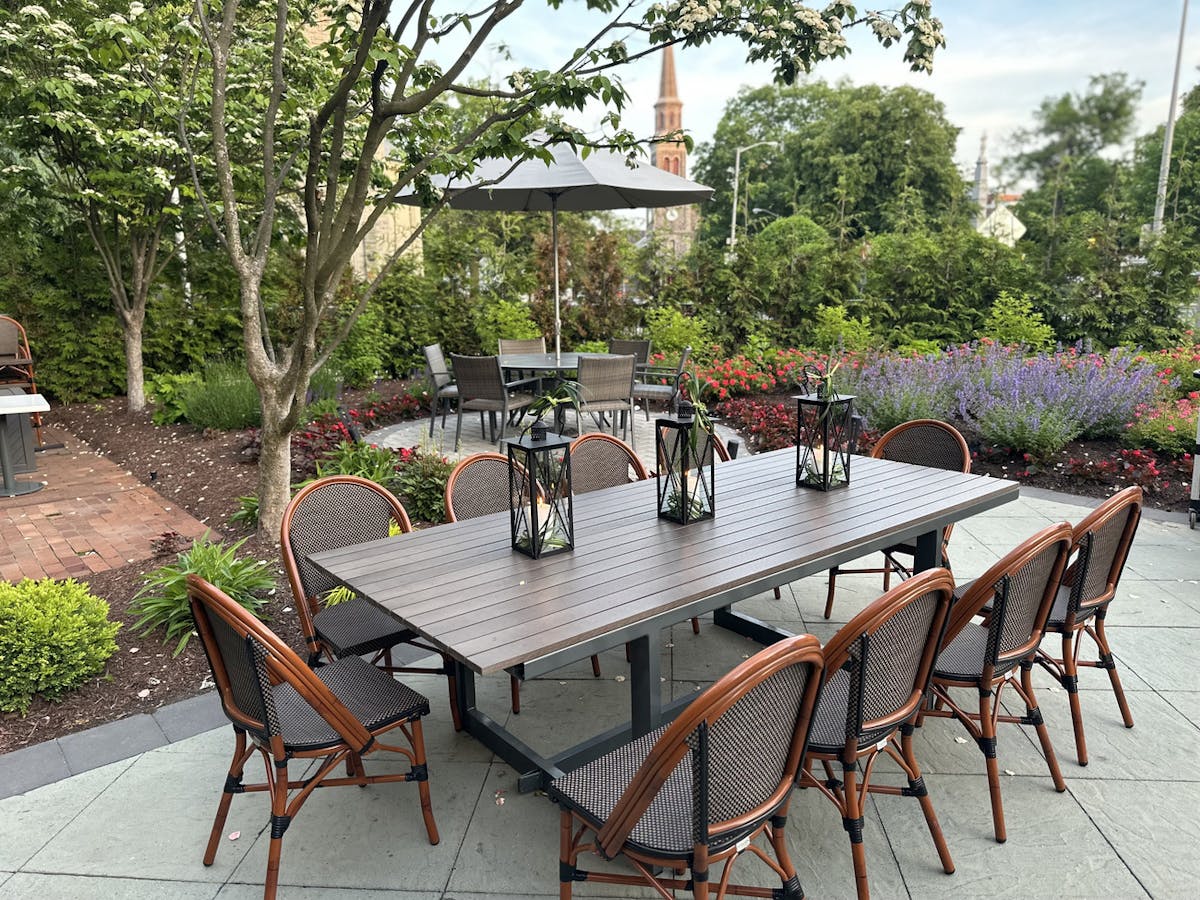 A patio with a table, chairs, and colorful umbrellas providing shade for outdoor dining.