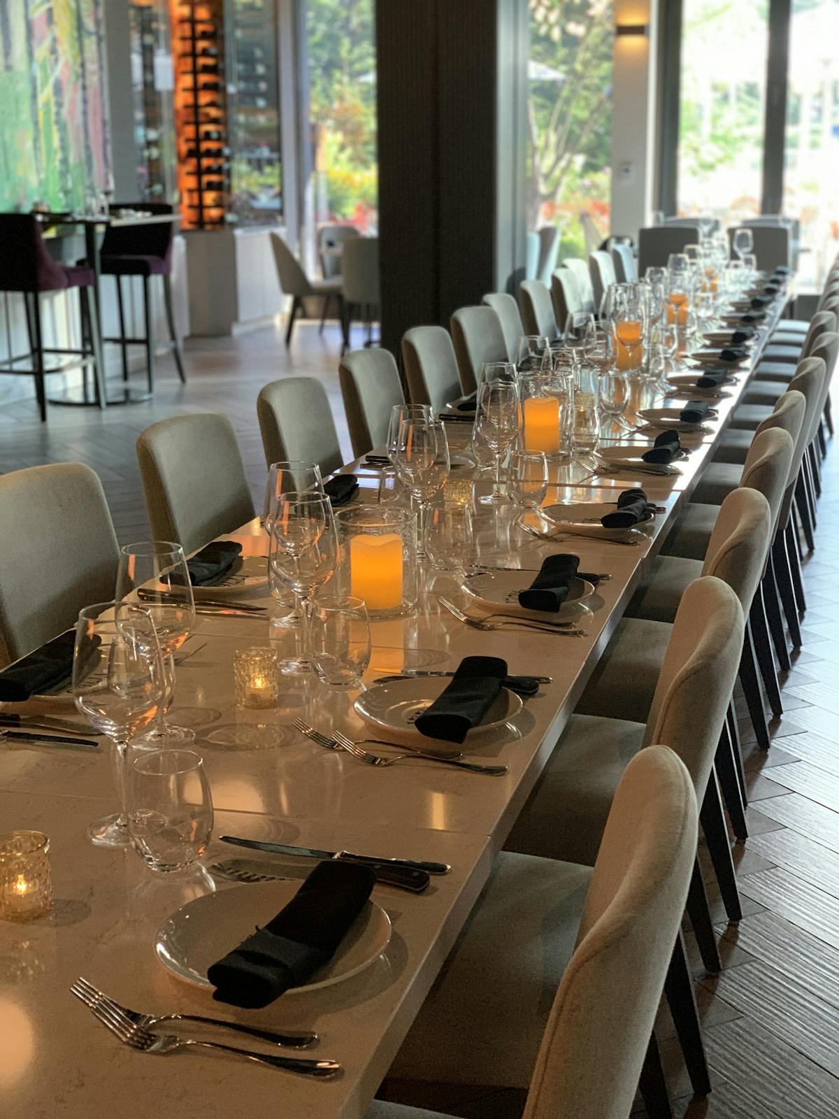 A long table set with numerous empty glasses and place settings, awaiting guests for a formal dining experience.