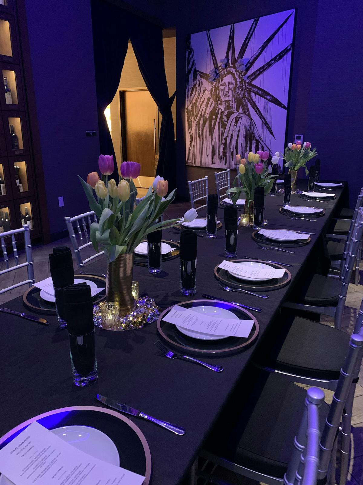 A beautifully arranged dinner table with elegant tableware, complemented by a captivating painting on the wall.