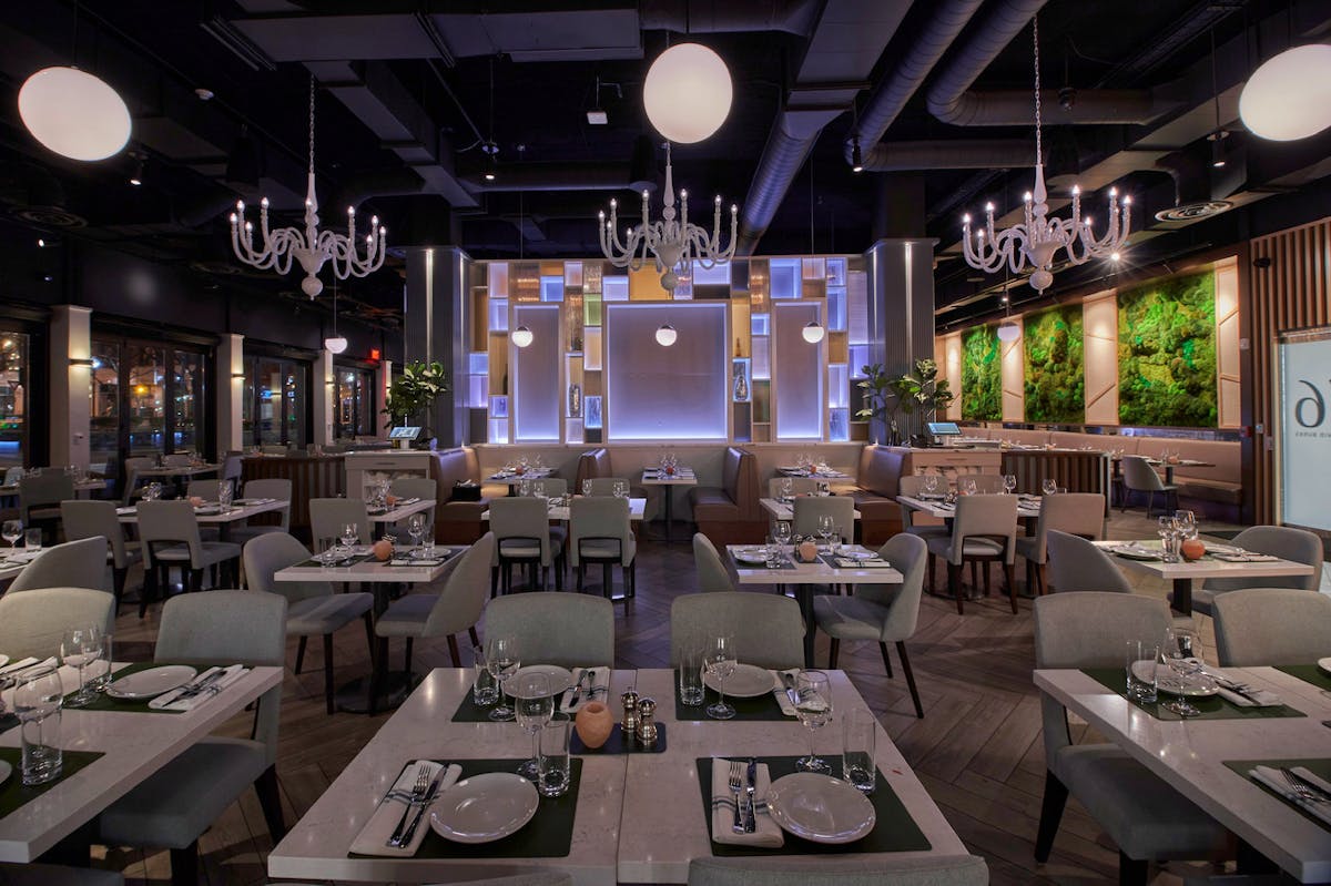 A restaurant interior featuring elegant tables and chairs adorned with chandeliers, creating a sophisticated dining atmosphere.