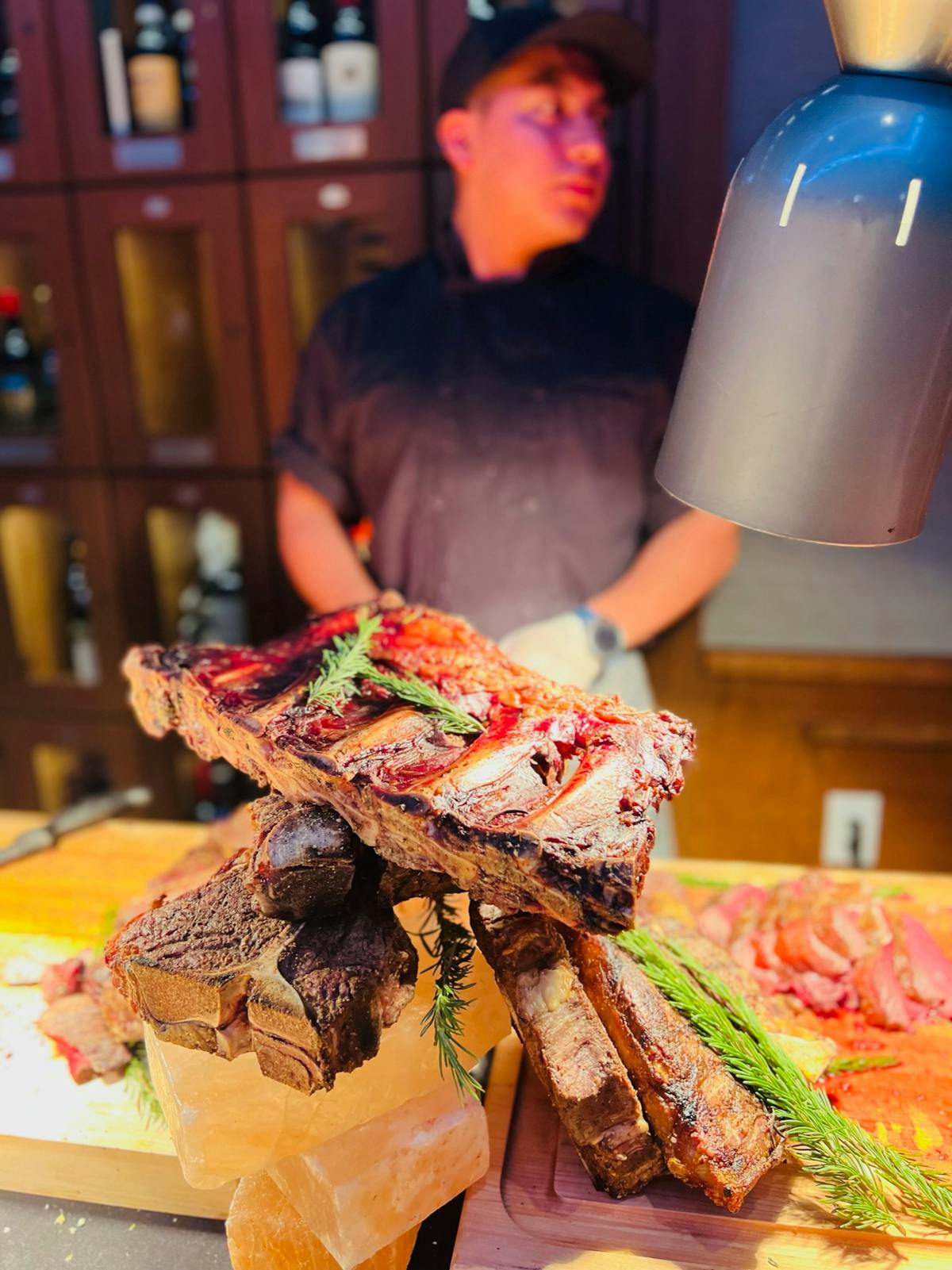 A man stands behind a table laden with various cuts of meat, showcasing a selection of fresh products.