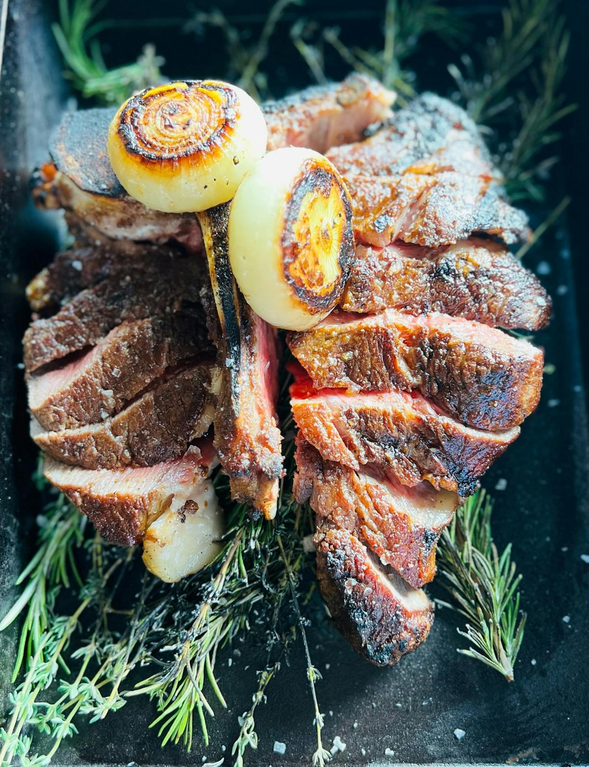 A beautifully cooked piece of meat topped with sautéed onions and a sprinkle of fresh herbs, enhancing its flavor and appeal.