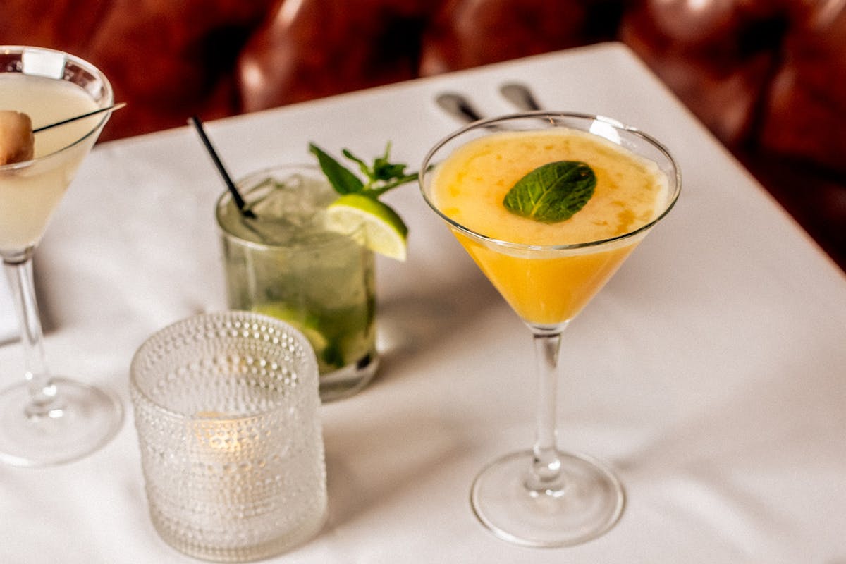 two cocktails on a white linen covered table
