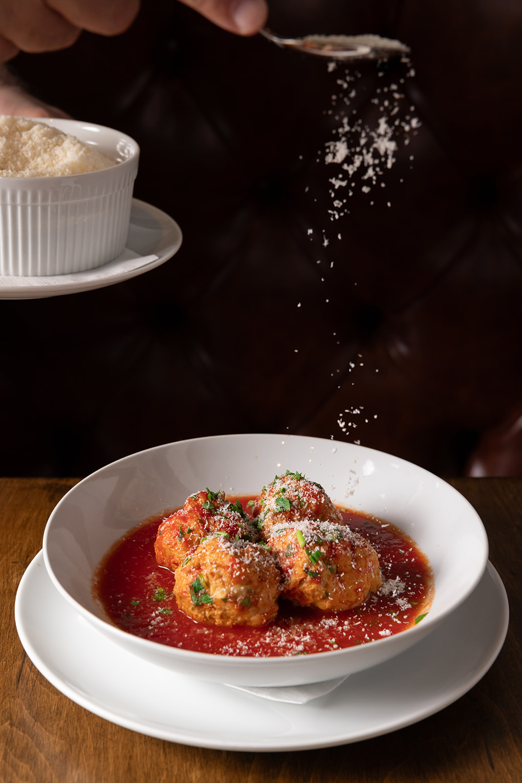 cheese being sprinkled on meatballs