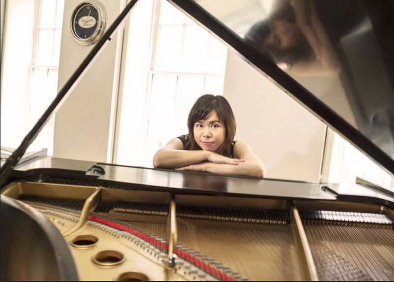 a woman leaning on a piano