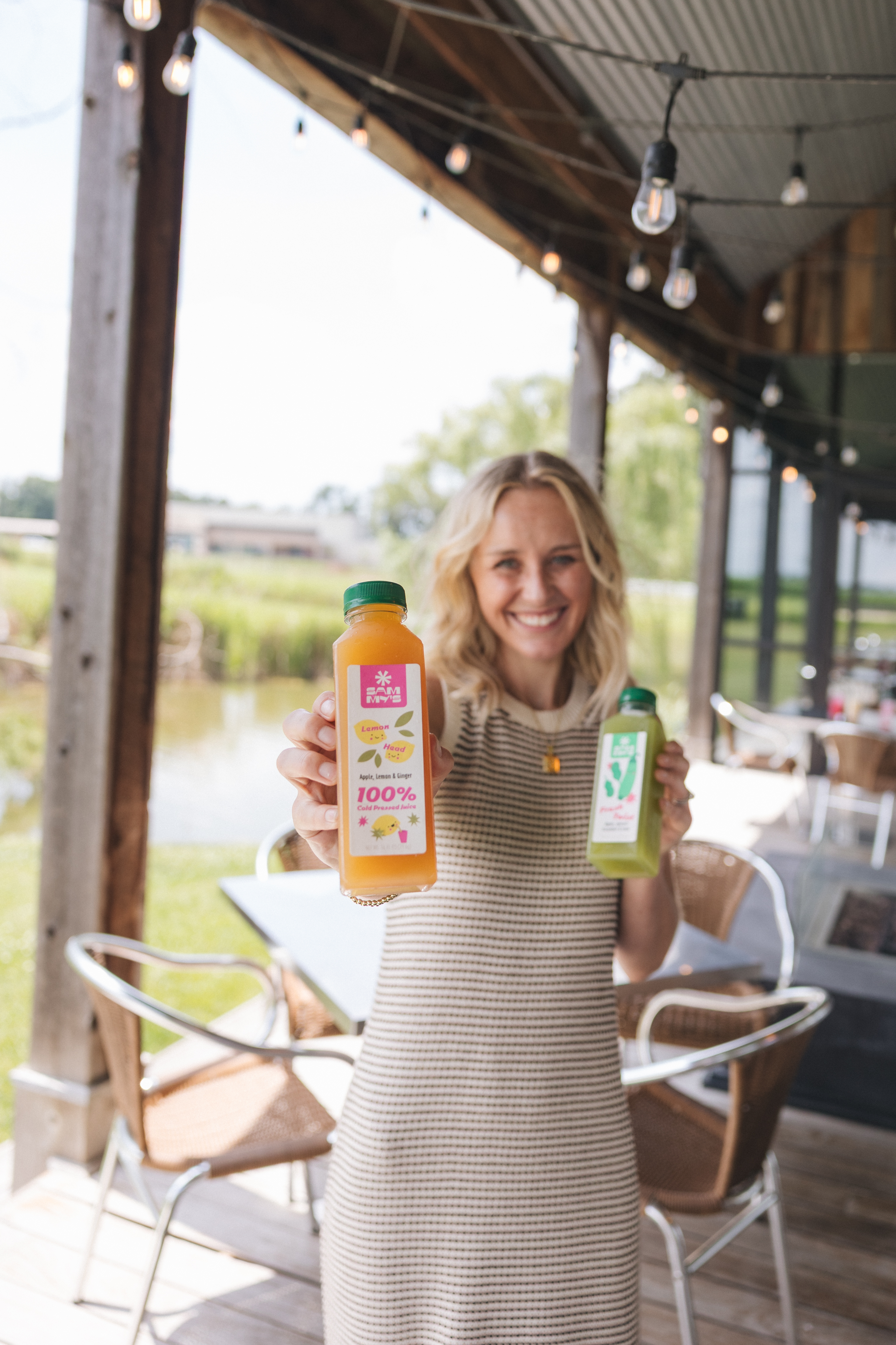 A woman holding two bottles of Sammy's juice on Firefly Grill's patio