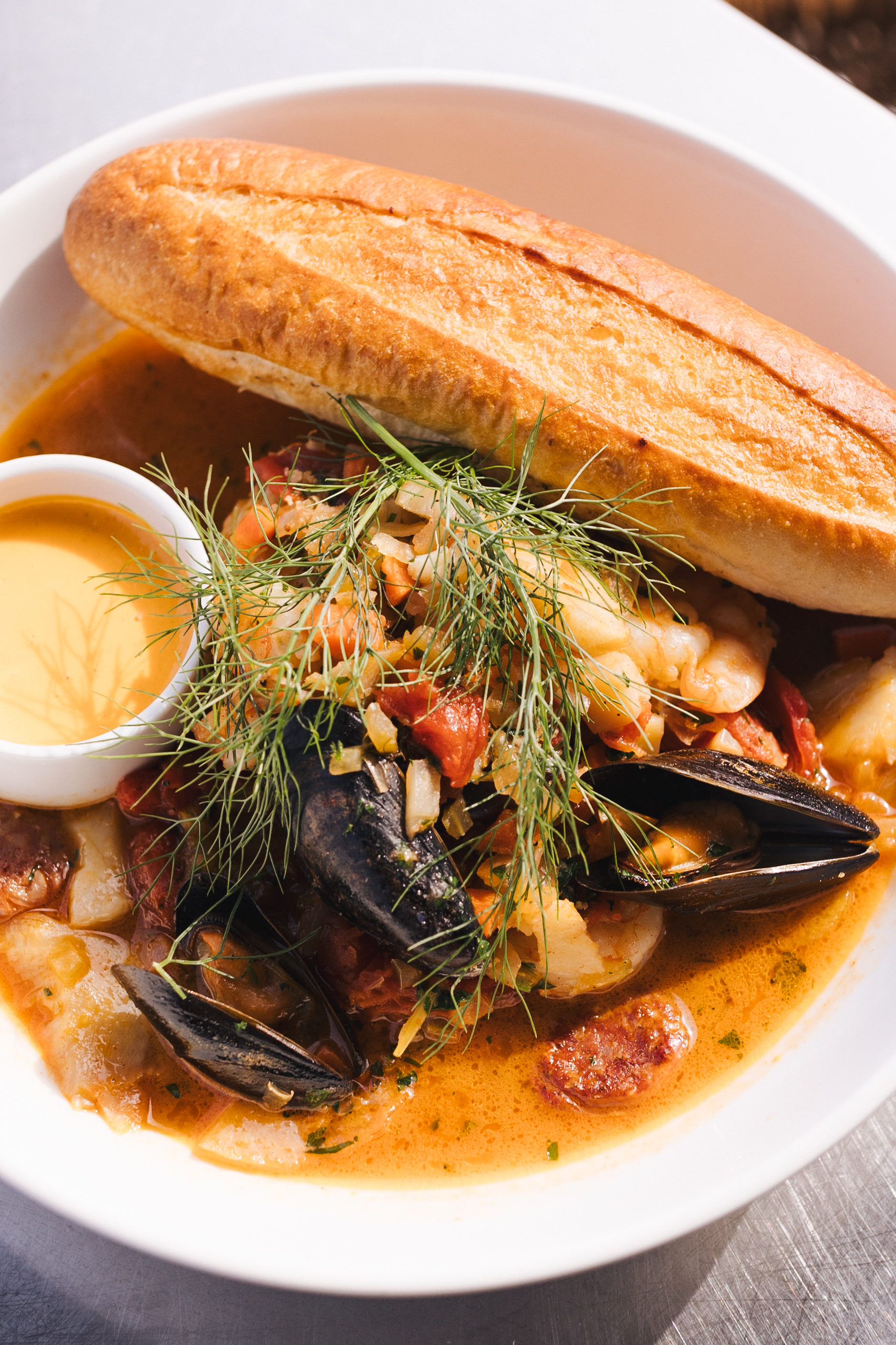 a bowl of soup with a loaf of bread and a sauce