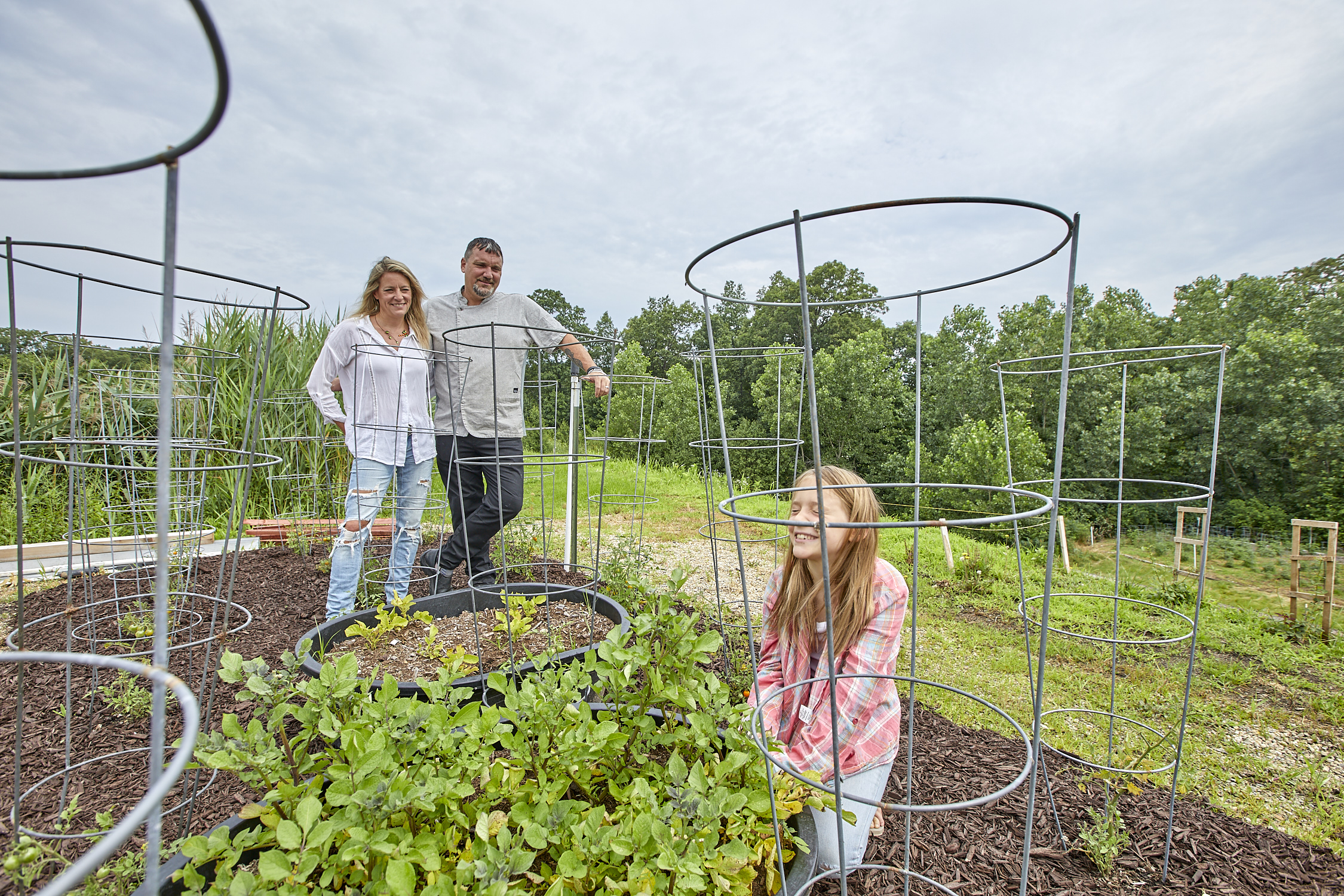 Niall and Kristie Campbell with their daughter tending tomato plants in Firefly Farm's garden