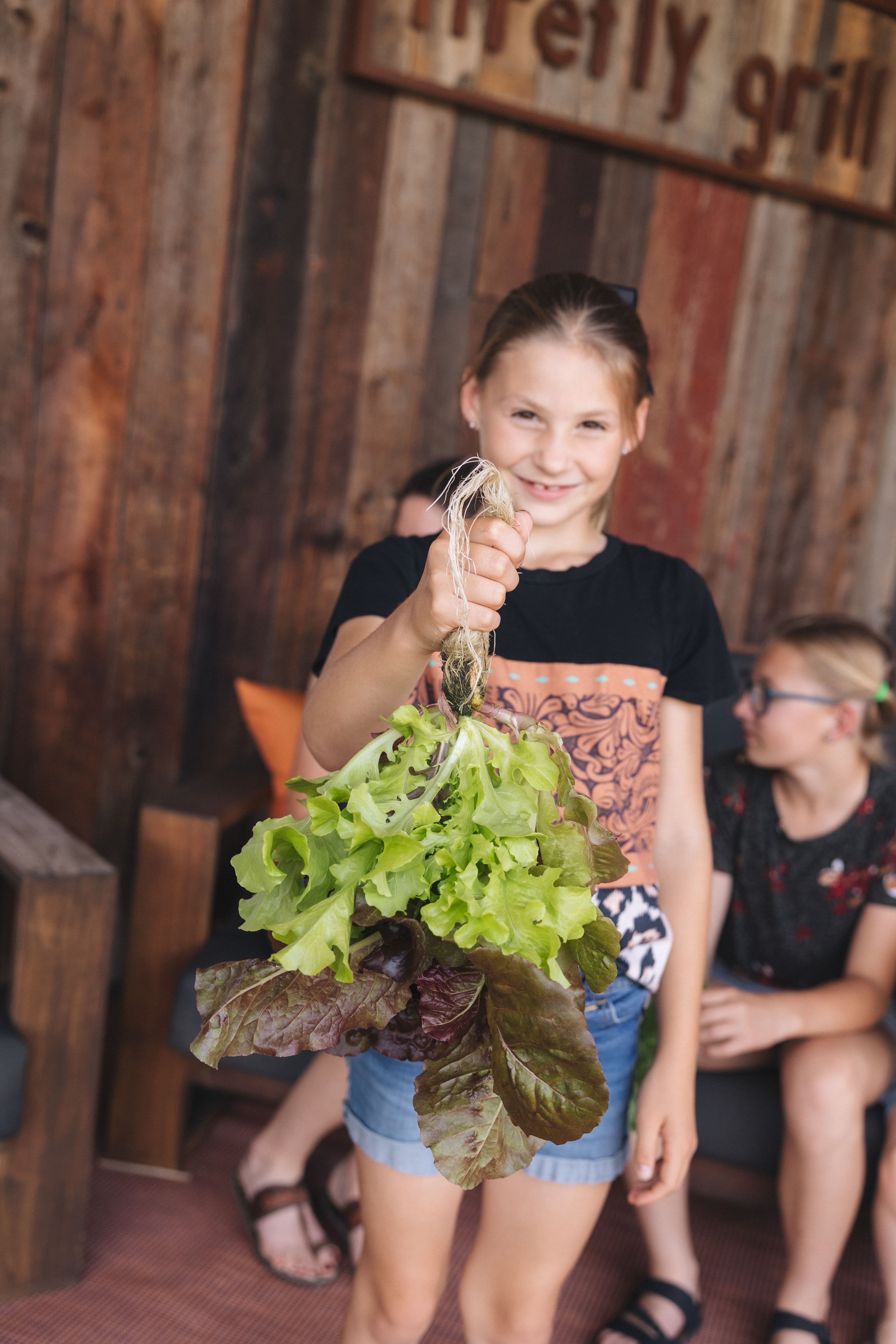 A young girl from Independence Acres holding a fresh bunch of harvested lettuce
