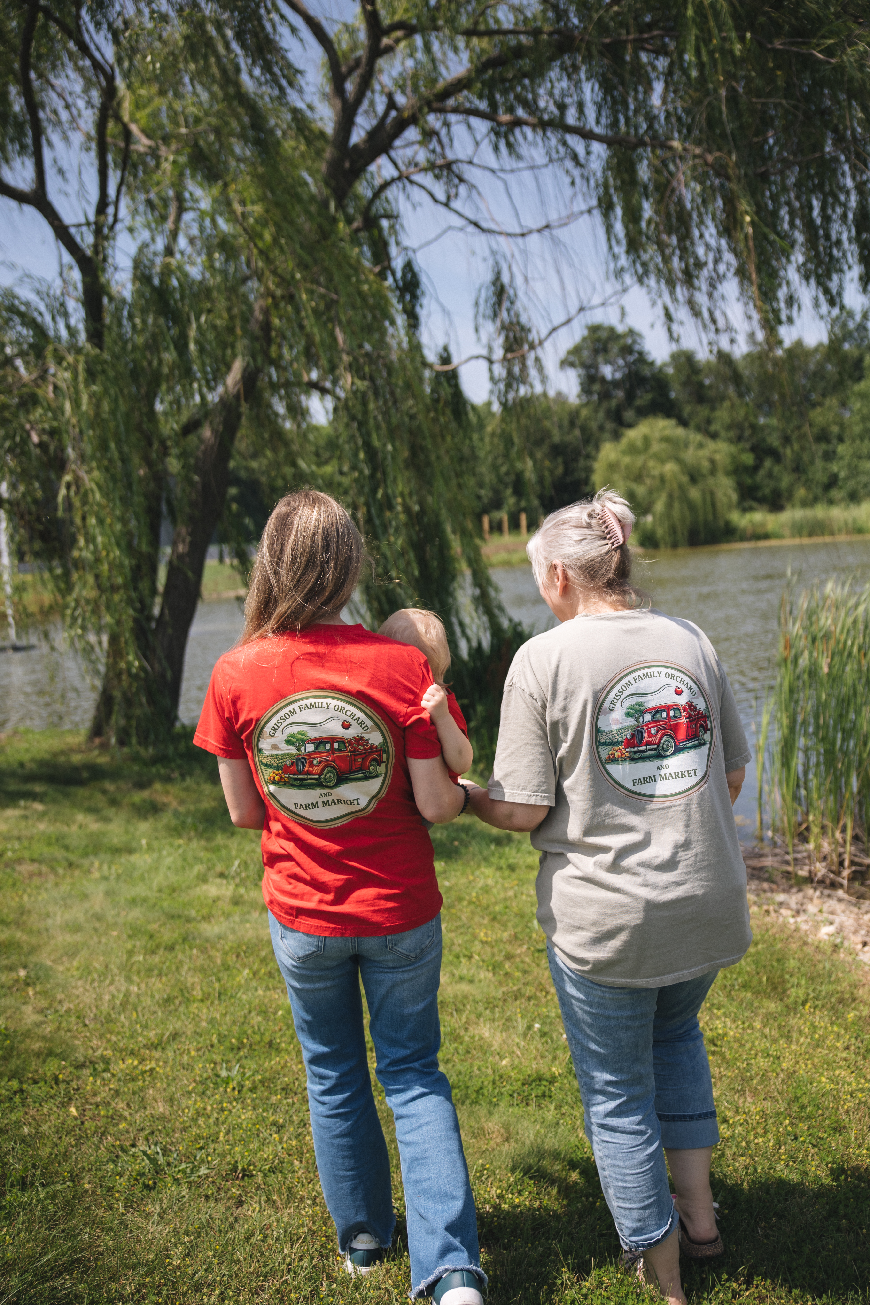 Two people in branded Grissom shirts walking along the water at Firefly Farm