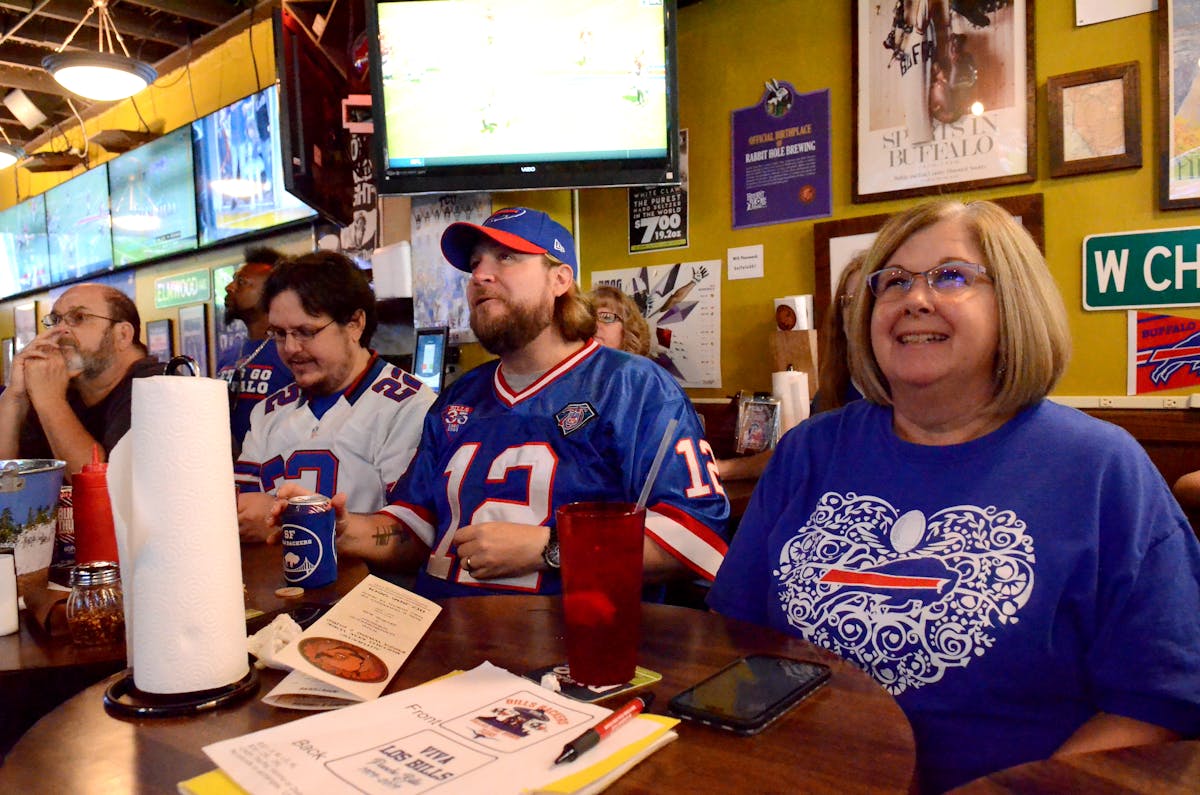 a group of people on a bar watching the TV