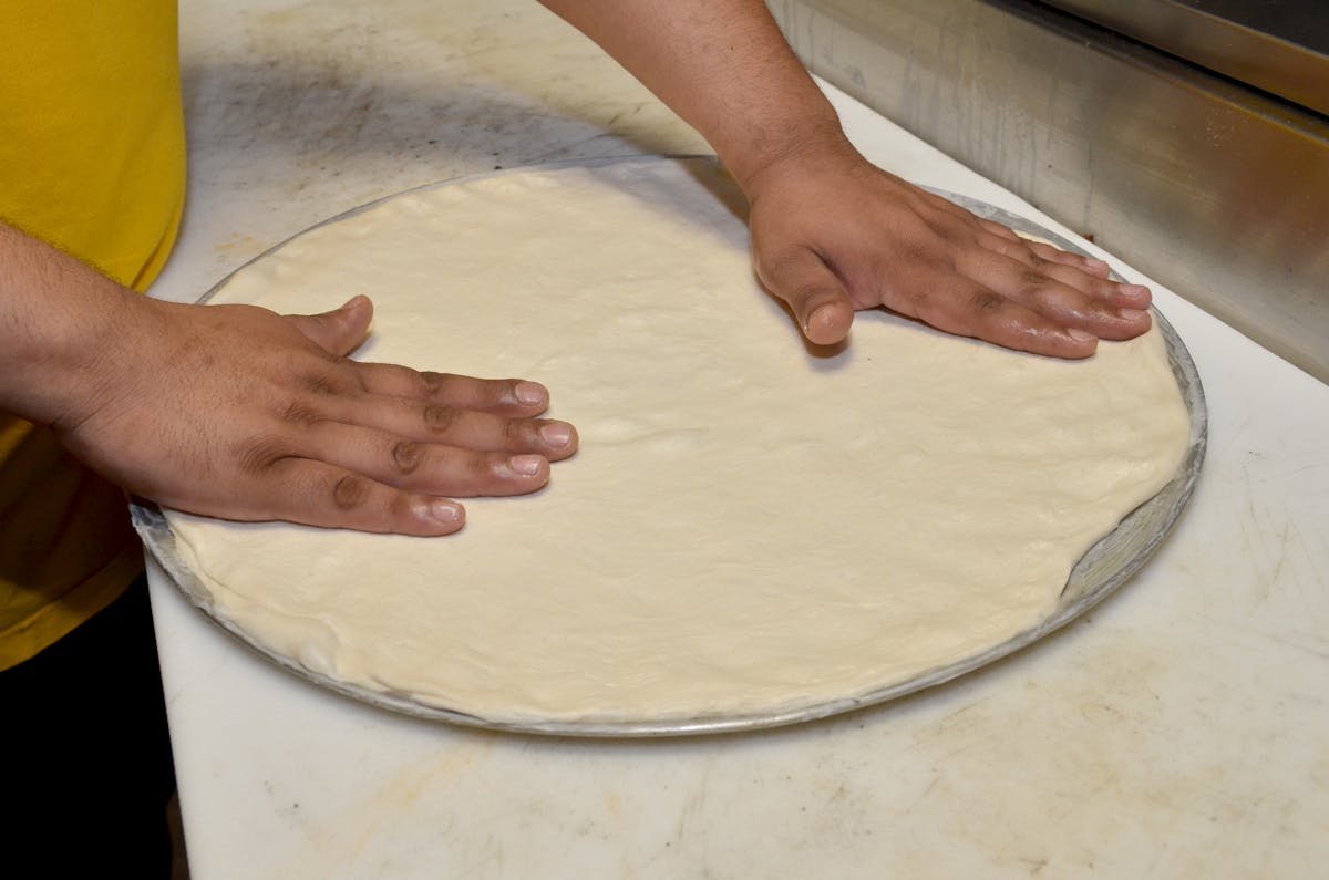 a chef making a pizza and sthretching a dough
