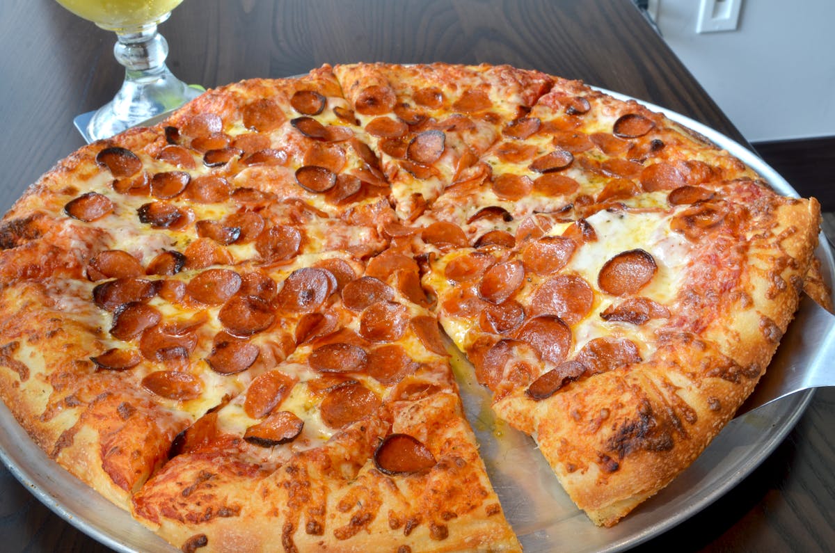 a crusty pepperoni pizza sitting on a metal pan