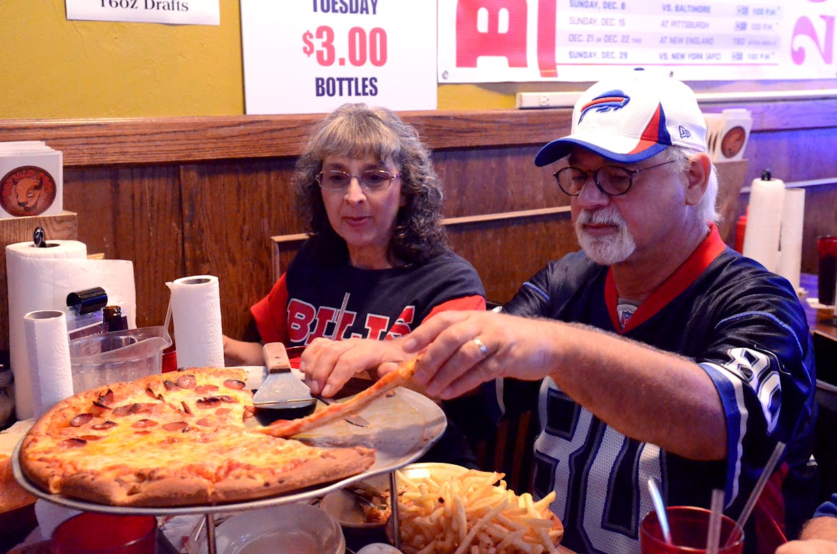 a couple cutting a slice of pizza