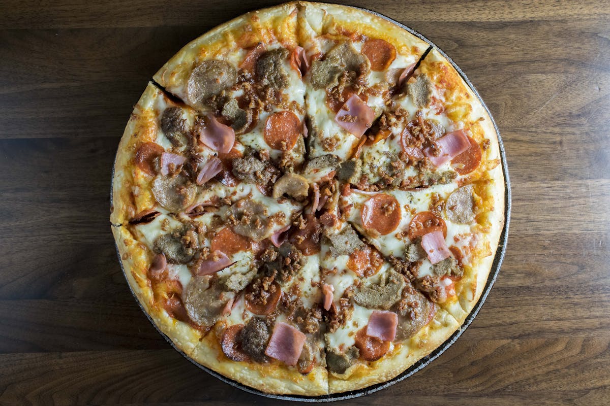 a mushroom,pepperoni and jam pizza sitting on a metal pan over a wood table
