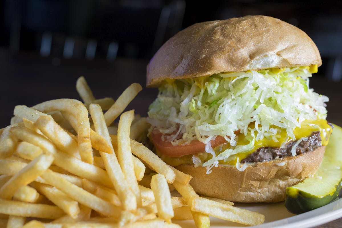 a plate of fries and a hamburger on the side, which is filled with vegetables and meat
