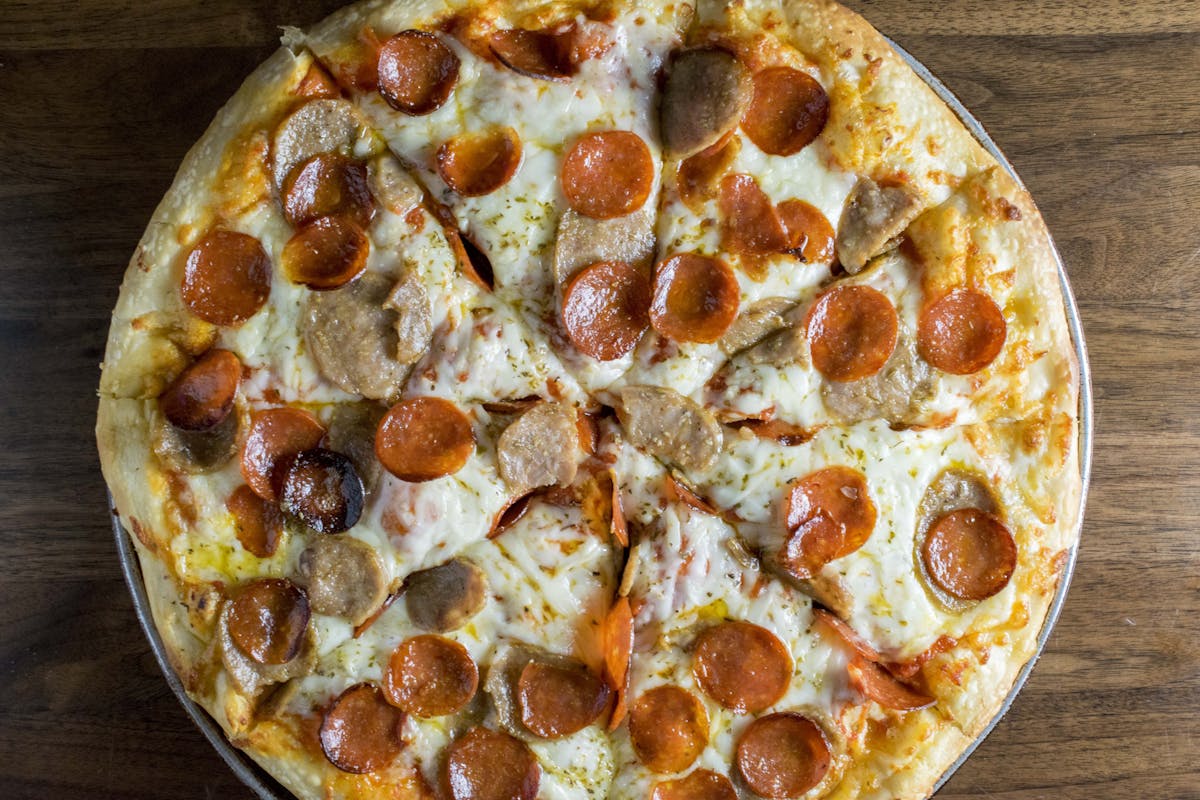a close up of a pepperoni pizza sitting on top of a wooden table
