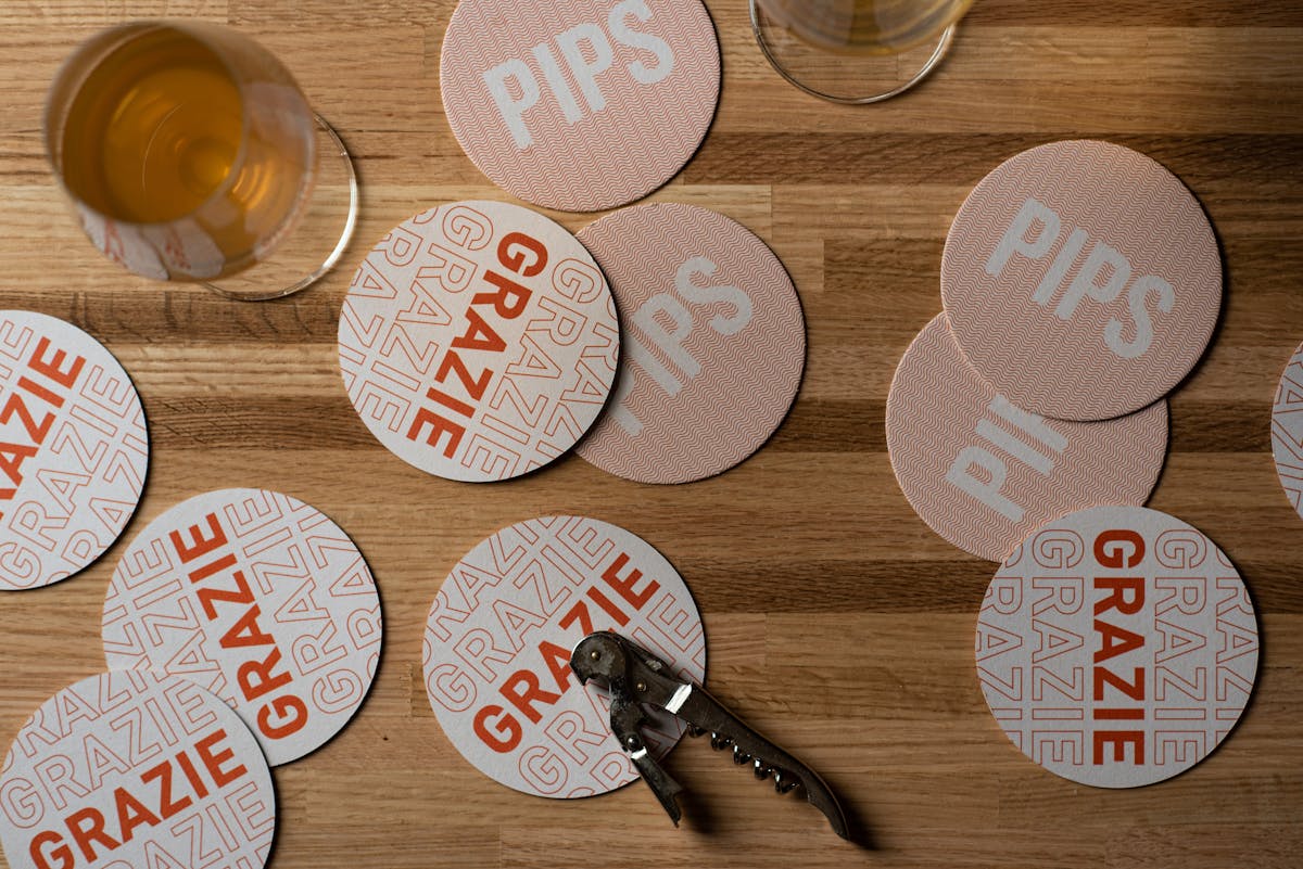Pips coasters laid out on a table with a wine key