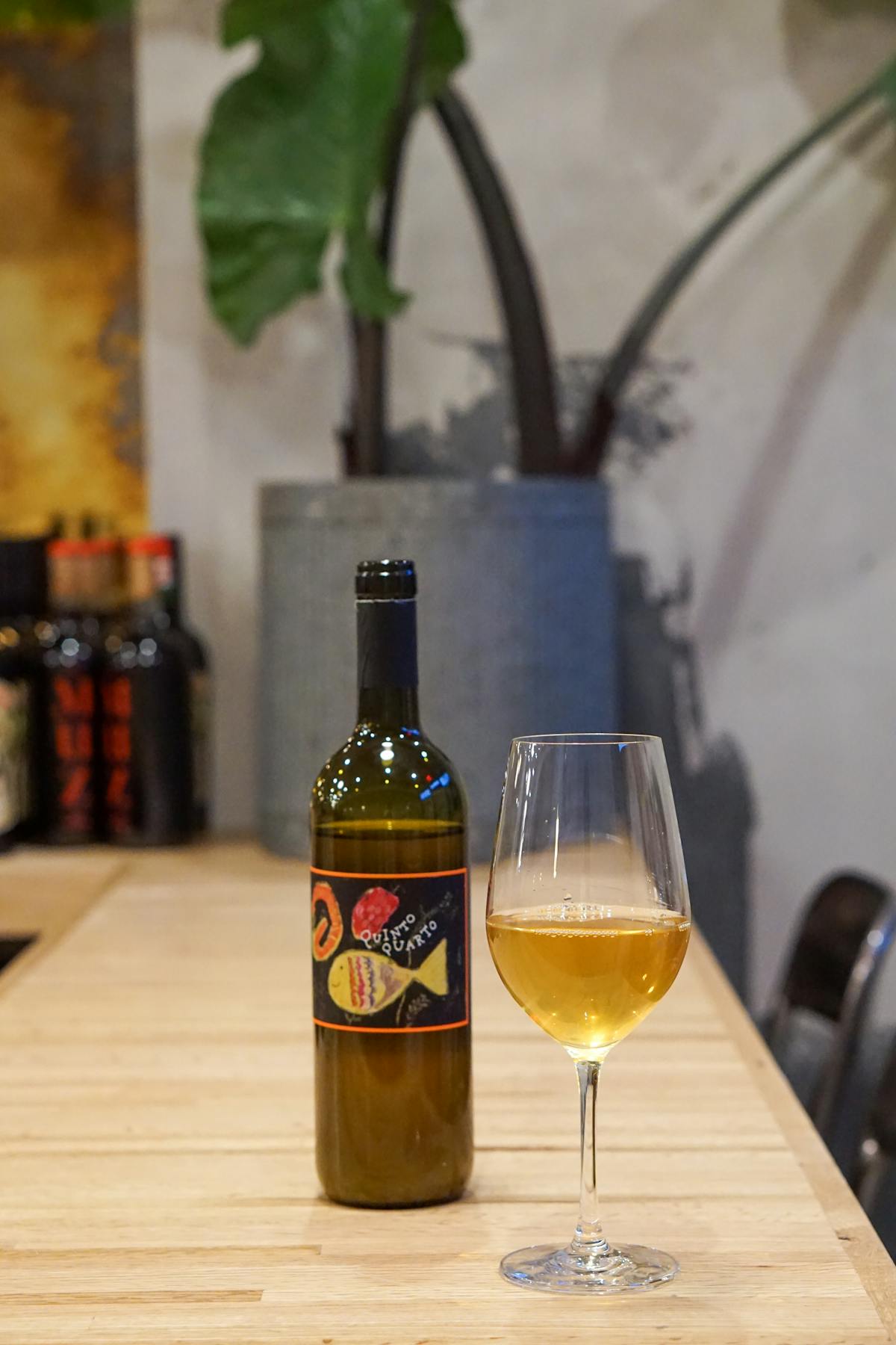 a bottle of natural orangewine from Italy, and a glass on a table