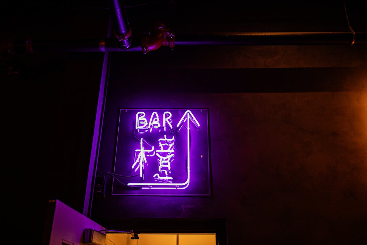 a sign in a purple light in a dark room
