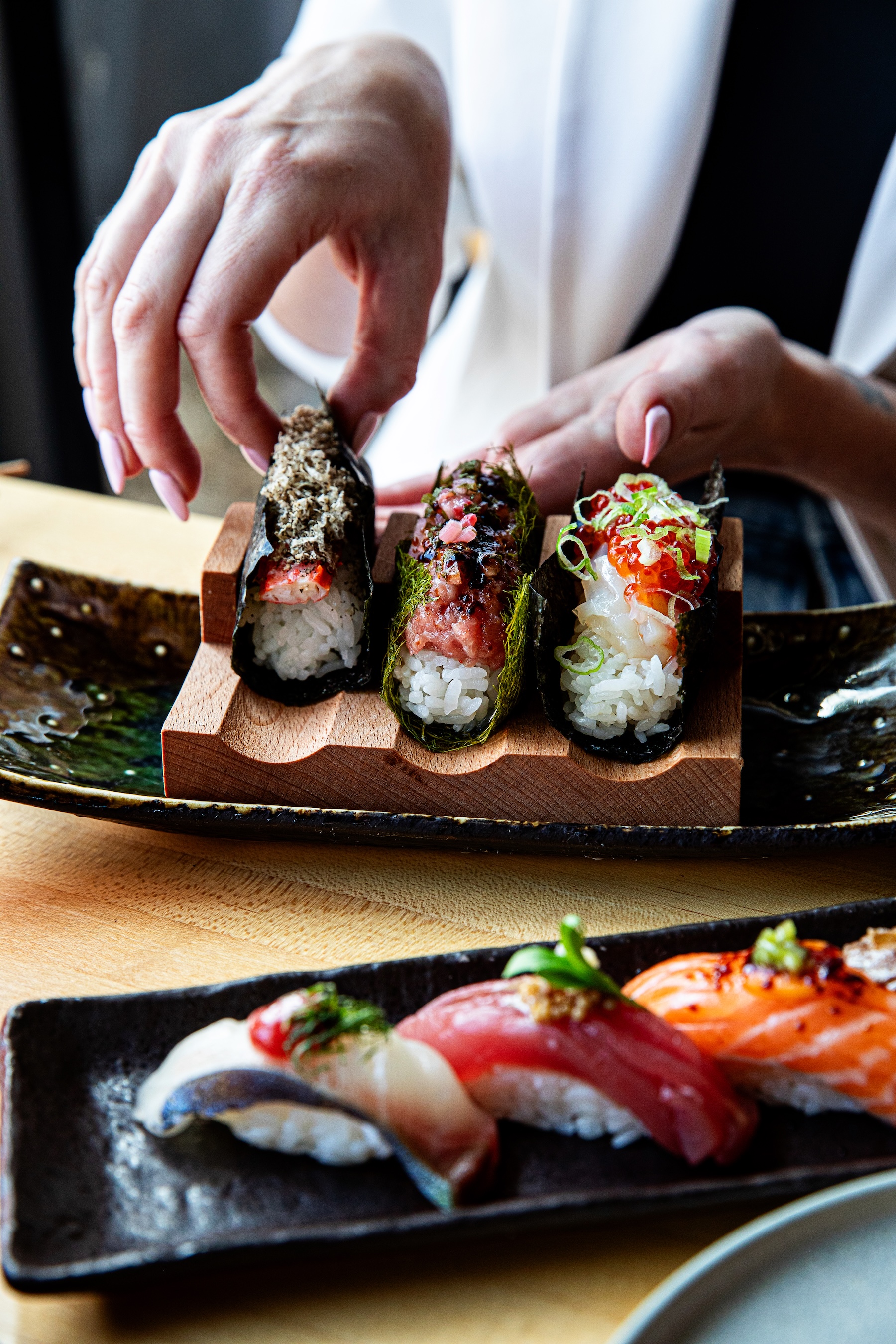 a person holding sushi on a plate
